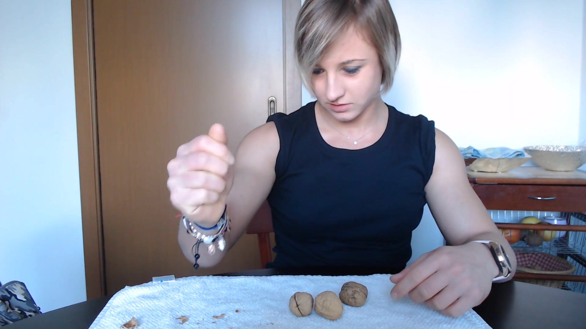 Muscle teen girl crushing walnuts with biceps